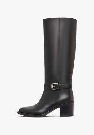 Zwarte leren kniehoge laars met een ronde neus, versierd met een gesp en een blokhak, met een gladde textuur en een slank ontwerp.