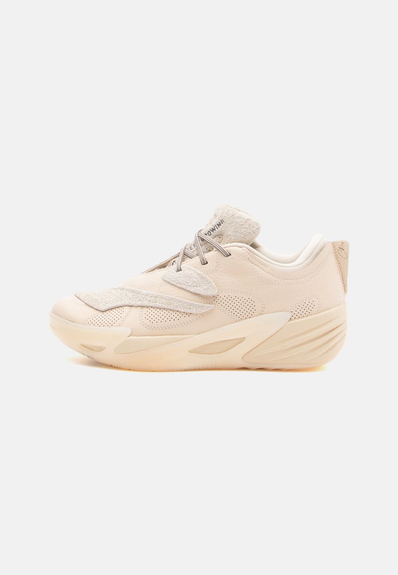 Beige atletiksko med mesh-paneler, en polstret krave og en struktureret sål. Har minimale detaljer og et glat, moderne design.