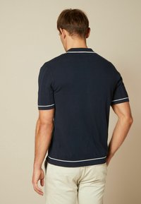 Laivaston lyhythihainen poolopaita, jossa on valkoinen reunus ja uritettu pinta, suora helma ja sovitettu muotoilu.