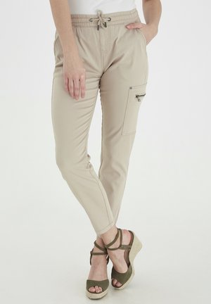 Beige cargo bukser med elastisk talje og snor, der har en sidelomme med lynlås og en tapered pasform.