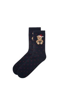 Marineblå sokker med en teddybj�ørn, der har en rød og hvid hat og små røde prikker. Lavet af blødt materiale, velegnet til afslappet brug.
