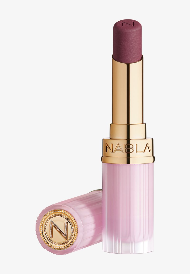 Rouge à lèvres mat mauve avec étui rose à côtes et détails dorés, nom de la marque NABLA gravé sur le tube et le bouchon, bouchon retiré et placé à côté.