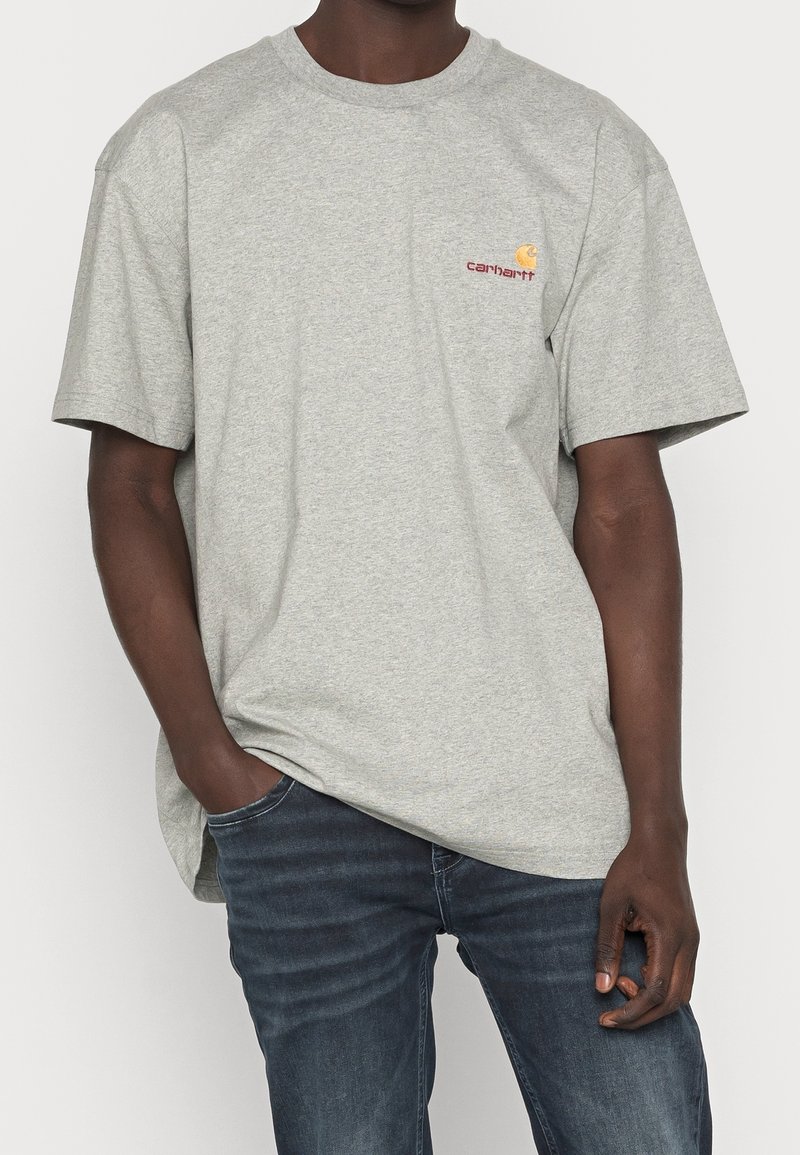 Szary t-shirt z krótkim rękawem, wykonany z mieszanki bawełny, z okrągłym dekoltem. Posiada małe logo Carhartt na lewej piersi. Luźny krój.