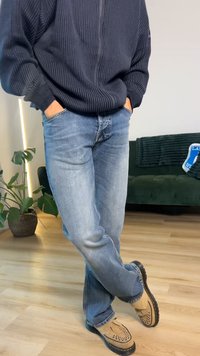 Blugi bleu deschis din denim cu croială dreaptă, asortați cu un pulover texturat închis la culoare. Încălțămintea este din piele întoarsă de culoarea caramelelor, cu decupaje decorative.