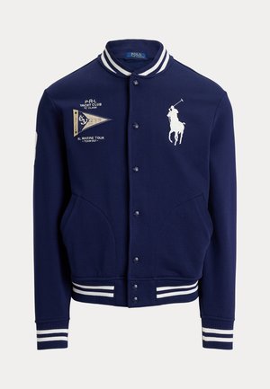 Tmavomodrá varsity bunda s bielo pruhovaným golierom a manžetami, predné vrecká, vyšívané logo hráča póla a text jachtového klubu s malou vlajočkou.