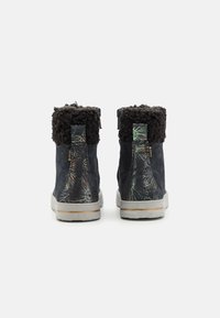 Botas de ante azul con un puño de piel de fur negro texturizado, que presentan un patrón floral en el tacón y una suela de goma blanca con un acento marrón.