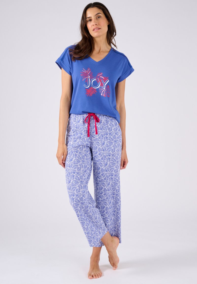 Camisa de algodón azul con cuello en V y texto rojo "JOY", combinada con pantalones de pijama blancos y azules con un patrón y cintura con cordón.