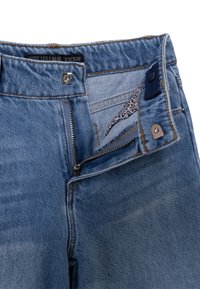 Jeans a gamba larga in denim azzurro chiaro con zip, chiusura a bottone e una tasca interna con motivo leopardato.