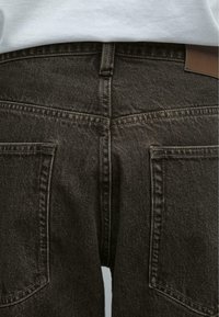 Mörkbruna jeans i denim med en klassisk femficksdesign, synlig sömnad och en läderlapp på midjebandet.