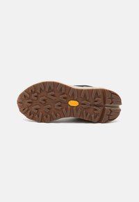 Juodas žygių batų padas su giliais, šiurkščiais dantukais, užtikrinančiais sukibimą, su rudu guminio pagrindo ir aiškiai matomu Vibram logotipo. 