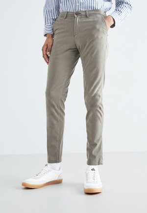 Chinos in misto cotone grigio chiaro, con una vestibilità slim; presentano tasche anteriori, una chiusura a bottone e cuciture a contrasto. Indossati con sneakers bianche.