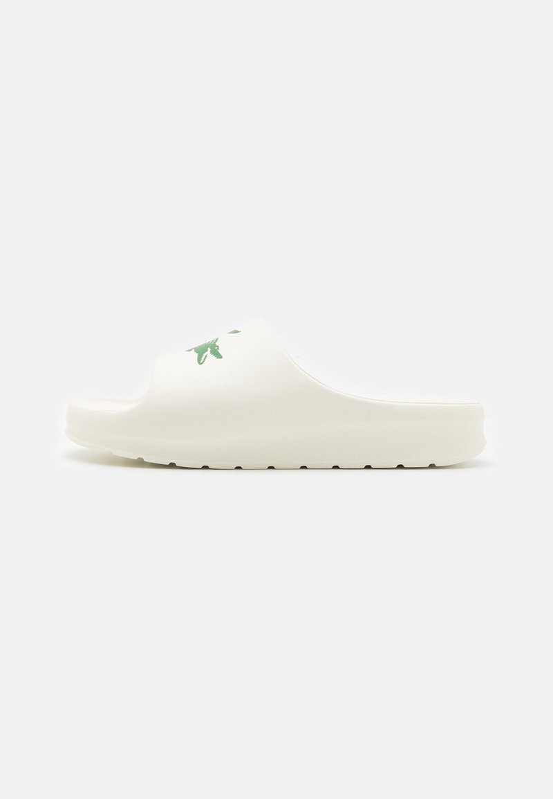 Sandale slide blanche avec une semelle épaisse et un logo vert sur la bride supérieure, vue de côté sur un fond uni.