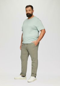 Lichtblauw t-shirt met korte mouwen en een ronde hals, gecombineerd met lichtgrijze broek en witte sneakers; gladde textuur, ontspannen pasvorm.