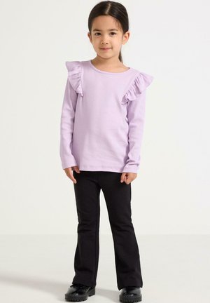 Langærmet lilla t-shirt med rynkede skulderdetaljer, parret med sorte flared bukser og sorte sko. Glat stof med ribbet tekstur.