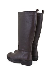 Braune Lederstiefel bis zum Knie mit strukturiertem Finish, flache Sohlen und Ziehschlaufenelementen oben für ein einfaches Anziehen.