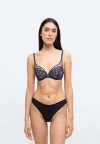 Σουτιέν σε ναυτικό μπλε με δαντέλα, μπανέλα για στήριξη και ρυθμιζόμενα λουριά. Μαύρο σλιπ χαμηλής μέσης που συμπληρώνει το σχέδιο του σουτιέν.