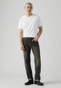 Witte katoenen t-shirt gecombineerd met donkergrijze denim jeans. Zwarte leren laarzen maken de outfit compleet, met een rechte pijp en subtiele slijtage.