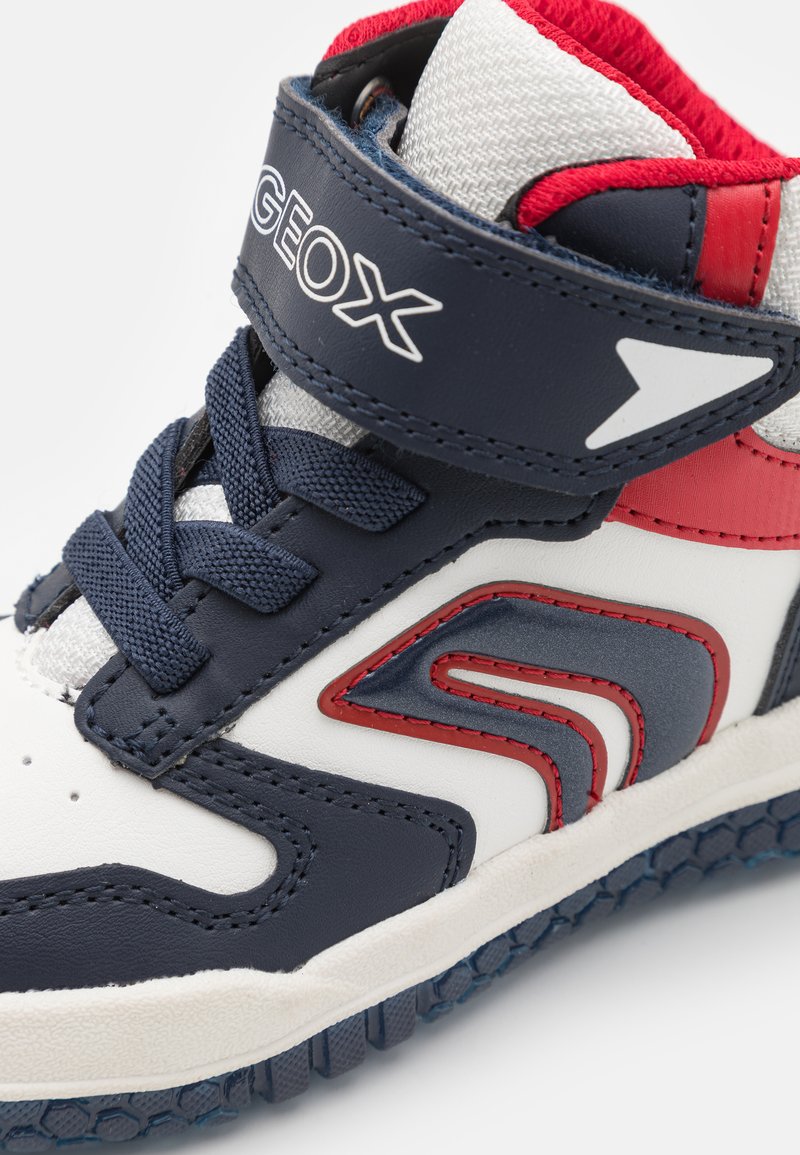 Hochschuhe in marineblauem und weißem Leder mit roten Akzenten. Verfügt über einen Klettverschluss und eine strukturierte Gummisohle mit hexagonalem Muster.