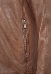 Braune Lederjacke mit einer seitlichen Reißverschlusstasche und silbernen Beschlägen, glatter Textur und detaillierten Nähten entlang der Nähte.