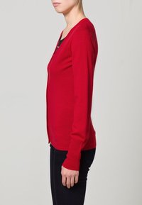 Cardigan rosso a maniche lunghe con design aderente e scollatura a V, realizzato in un tessuto morbido e leggero. Senza fasteners visibili o decorazioni.