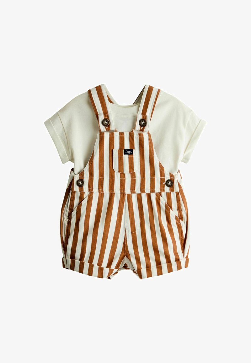 T-shirt crème à manches courtes associé à une salopette courte rayée verticale marron et blanche avec des boutons et une poche avant.