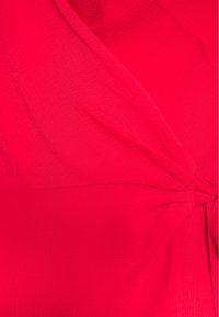 Tissu rouge vif, texturé avec un design plissé. Présente un détail en nœud sur un côté, soulignant la douceur et la fluidité.