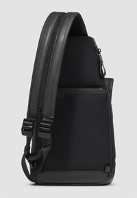 Zwarte schoudertas met een textuurstof, gladde leren accenten, dubbele ritsen en verstelbare bandjes voor veilig dragen.