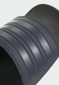 Round, navy blue slide sandal with ridged texture on the upper and a smooth, curved sole made of a flexible material.