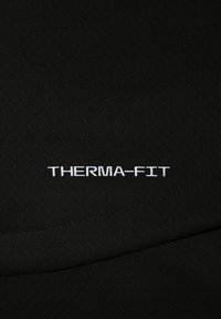 Tela negra con el texto "THERMA-FIT" bordado en blanco, destacando el detalle de la tecnología de ajuste térmico en el material de la ropa.