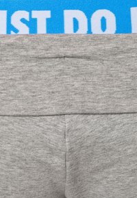Fascia in tessuto grigio con una superficie testurizzata. Presenta una banda blu con testo bianco "JUST DO IT". Design semplice e funzionale.