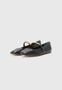 Ballerines en cuir noir avec un bout pointu, dotées d'une fine sangle noire et d'un accent doré sur le dessus. Semelle plate, texture lisse.
