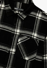 Czarna i biała sztruksowa koszula w kratę z kołnierzykiem, z przodu na guziki i kieszenią na piersi. Miękka tekstura z wyraźnym wzorem kratki. Regularny krój.