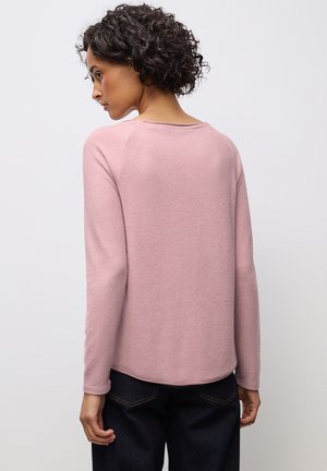 Rosa langärmliges Oberteil mit rundem Halsausschnitt, weichem Material und abgerundetem Saum. Kombiniert mit dunklen Jeans, von hinten betrachtet.