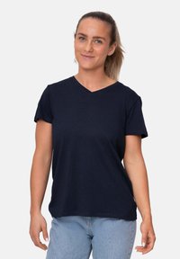 T-shirt blu navy a V in morbido tessuto, con maniche corte e vestibilità rilassata, indossata con jeans azzurri.