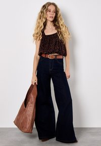 Brun leopardmönstrad kort topp, högmidjade mörka denim jeans med utsvängda ben, brun läderbälte och överdimensionerad brun läderväska.