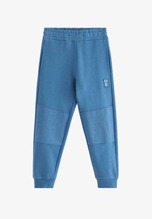 Pantalon de survêtement bleu en tissu doux, doté de panneaux texturés aux genoux, de poches latérales et d'une ceinture élastique.