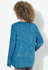 Maglione color teal con minuscole macchie d'argento sparse, maniche lunghe, colletto tondo e una texture morbida. Progettato per una vestibilità comoda e casual.