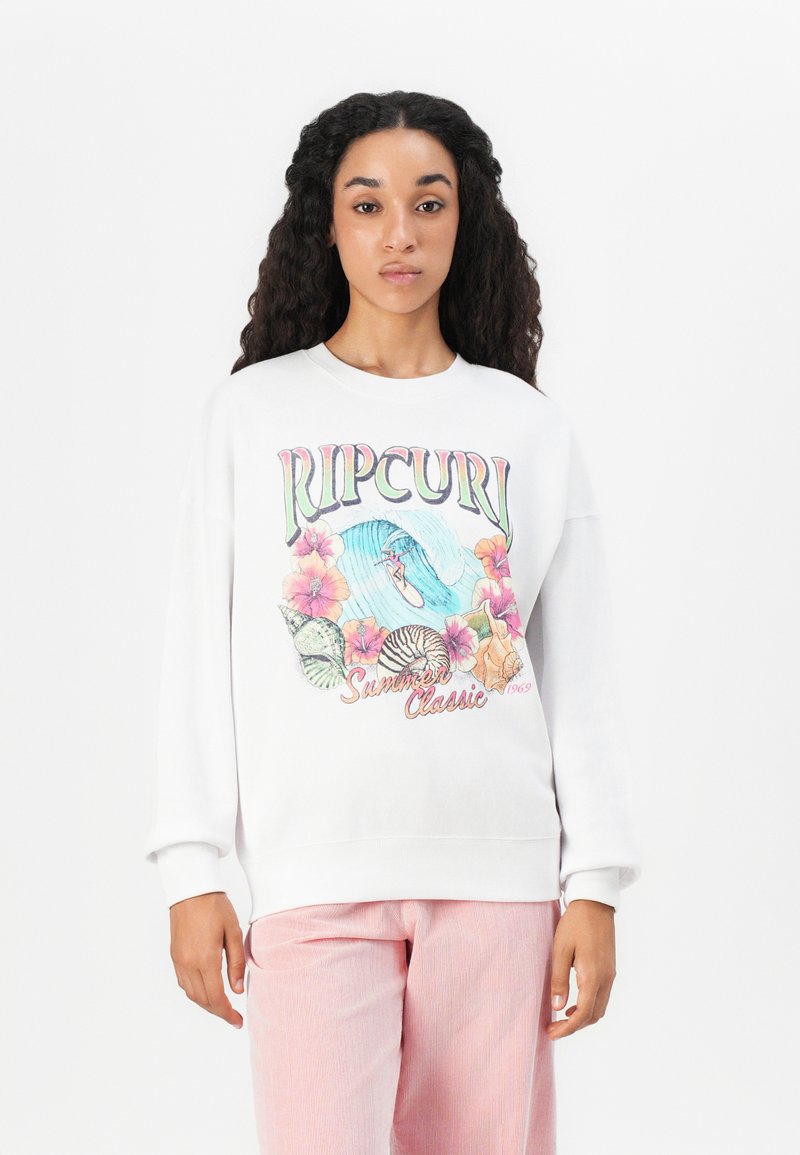 Felpa bianca con grafica colorata che presenta onde, fiori e conchiglie; vestibilità comoda con polsini e vita a coste. Abbinata a pantaloni a righe rosa.