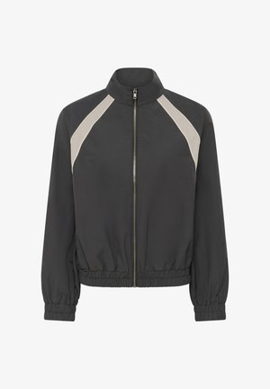 Veste noire zippée avec poignets et ourlet élastiqués, ornée de rayures diagonales beige clair sur les épaules.