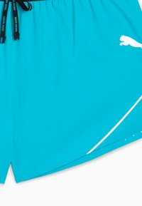 Türkise Sportshorts mit schwarzem Kordelzug, weißem Logo und diagonaler weißer Streifenverzierung am Saum. Glatte Textur, leichtes Material.