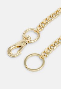 Chaîne en métal doré avec un grand design de maillons, dotée d'un fermoir mousqueton à une extrémité et d'un anneau rond à l'autre pour l'attache.