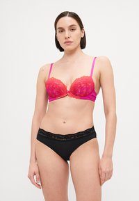 Bh i rosa og oransje med blonder-overlegg og justerbare stropper, parret med svarte truser med blondekant på livet.