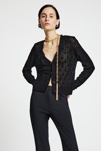 Schwarze Strickjacke mit Diamantmuster, tiefem V-Ausschnitt, Knopfverschluss und gerippten Ärmelbündchen. Mit einem goldenen Kettendetail verziert.