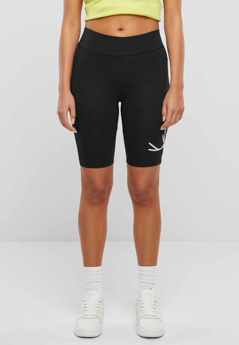 Schwarze Radshorts aus dehnbarem Stoff, mit hohem Bund und einem weißen grafischen Design am linken Oberschenkel.