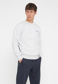 Sweatshirt gris en mélange de coton avec un col rond, des poignets et un ourlet côtelés, arborant un texte brodé en bleu sur la poitrine.