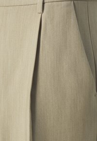 Beige tailored trousers with a textured fabric, featuring front pleats and a flat waistband design.