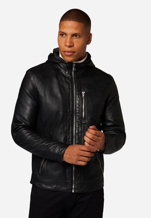 Veste en cuir noir avec capuche, dotée d'un zip sur le devant et de deux poches latérales. La texture est lisse, avec une coupe ajustée et des accents minimaux.