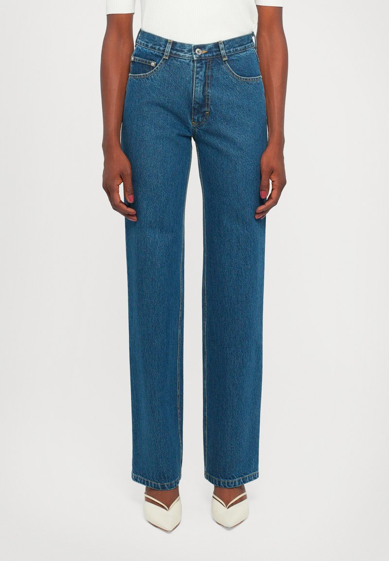 Wide-leg blue denim jeans with a high waist, contrasting stitching, and five-pocket design, finished with a raw hem detail.