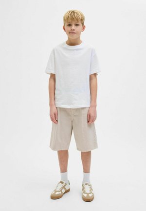 T-shirt en coton blanc, shorts en coton beige, chaussettes blanches et baskets beiges avec des accents marron. Design minimal, coupe simple et décontractée.
