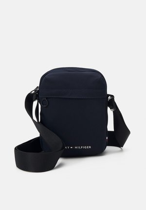 Navy blue crossbody bag made of durable fabric. Features a zip closure, adjustable strap, and a small logo detail on the front.